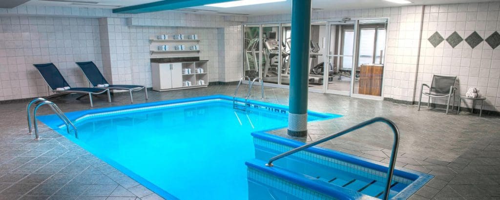 The small indoor pool at SpringHill Suites by Marriott Old Montreal, with two chairs resting nearby.
