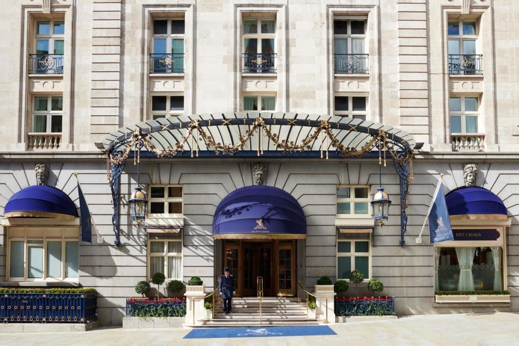 The exterior entrance to The Ritz London, featuring royal blue awnings overhead.