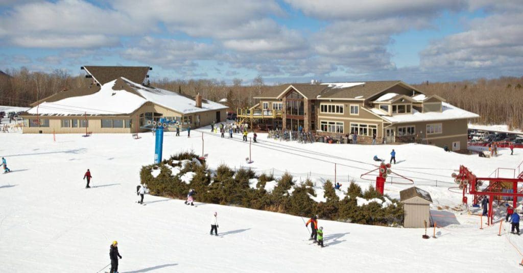An aerial view of Big Powderhorn Mountain Resort in the winter, with skiiers meandering through the grounds.