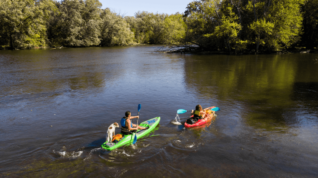 Two people kayak down a river in Kalamazoo, one of the best places to visit in Michigan with kids.