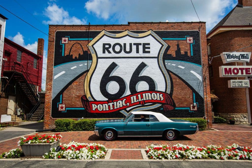 A Pontiac is parked in front of a sign for Route 66 in Southern Illinois.