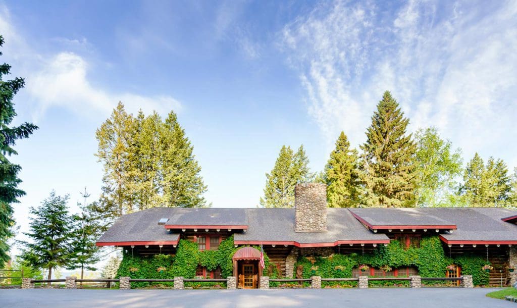 The ivy-covered exterior of the main lodge of Flathead Lake Lodge on a sunny, summer day, at one of the best all-inclusive hotels in the United States for families.