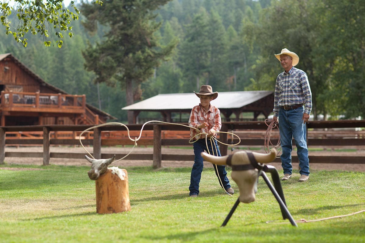 A dad and his young son rope target cattle, while staying at Flathead Lake Lodge.