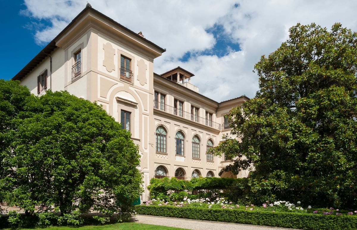 The grand exterior to Four Seasons Hotel Firenze, with large trees flanking the entrance.