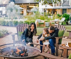 A family of three roasts marshmallows over a fire pit, while staying at Four Seasons Hotel Austin.