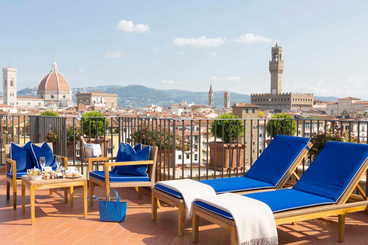 Blue loungers await guests at the rooftop terrace of Hotel Lungarno, with a sweeping view of Florence, including the iconic Duomo.