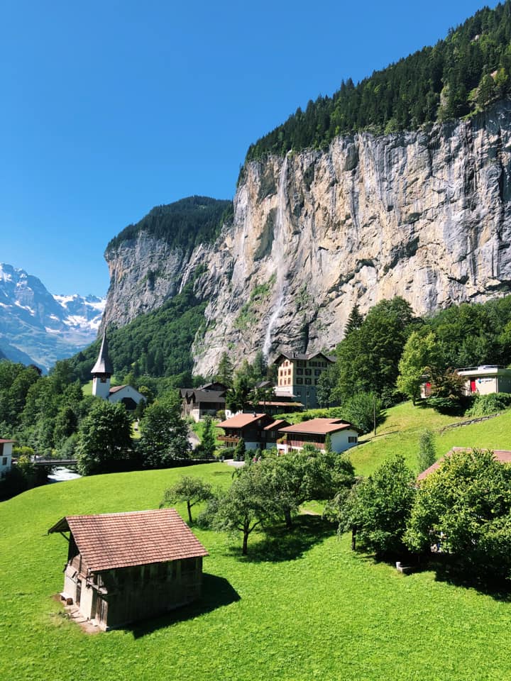 A charming view of green grass and traditional buildings near Lauterbrunnen on a sunny day.