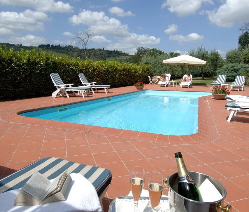 The outdoor pool, with a few white poolside loungers on the pool deck, at Marignolle Relais and Charme.