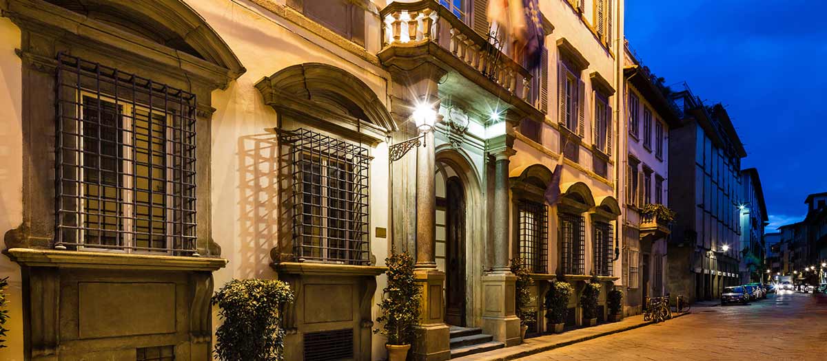 The exterior entrance to Relais Santa Croce by Baglioni Hotels, lit up at night.
