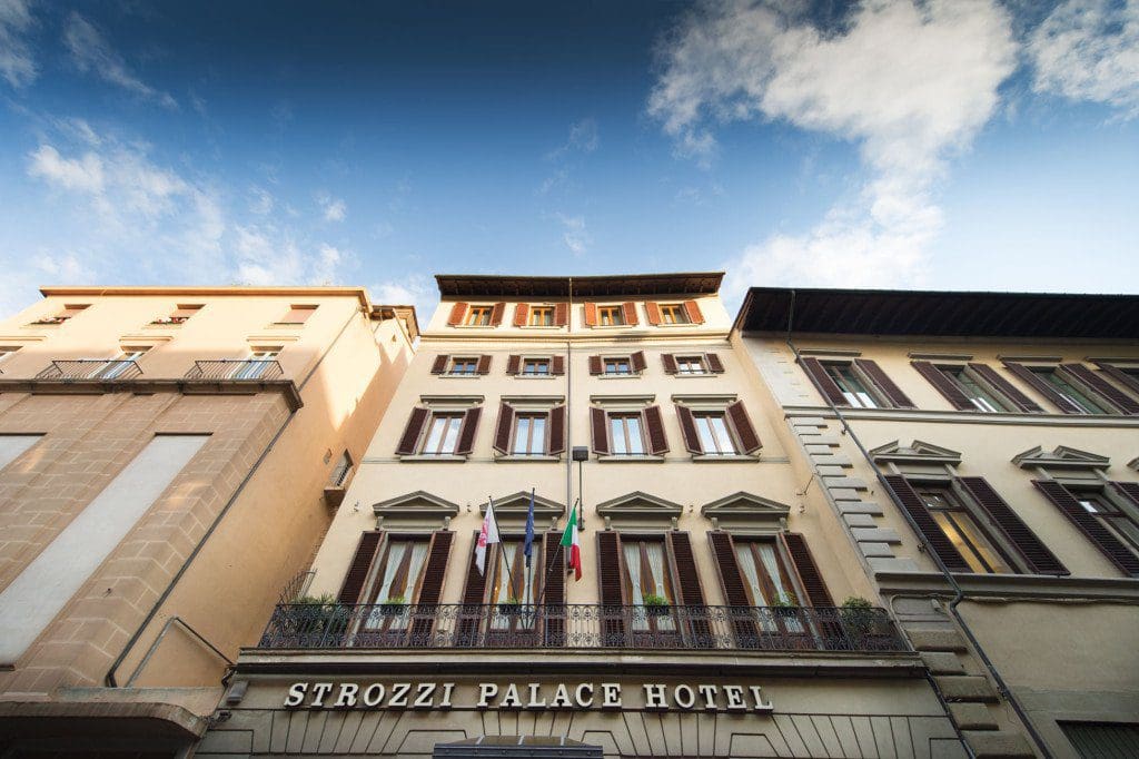 A skyward view of the exterior of Strozzi Palace Hotel, with clouds overhead.