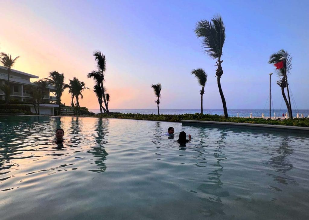 Two kids swim in the on-site Bamboo Pool at Four Seasons Resort and Residences Anguilla.