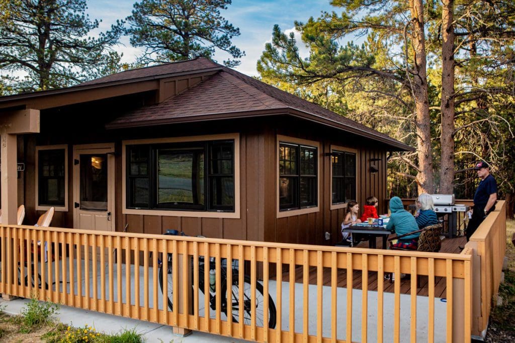 A family dines at a picnic table on the terrace of their cabin, while staying at YMCA of the Rockies Estes Park Center.