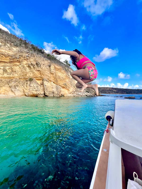 A young girl jumps from a boat into crystal clear waters offshore from Anguilla.