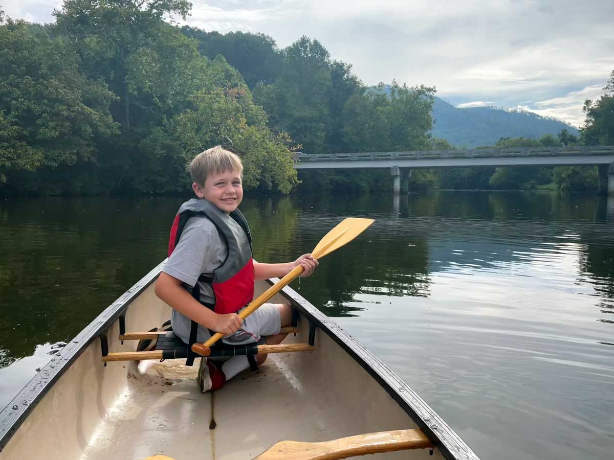 A young boy paddles a canoe, while exploring the river that runs through Blackberry Farm, while on a family getaway to Blackberry Farm in Tennessee.