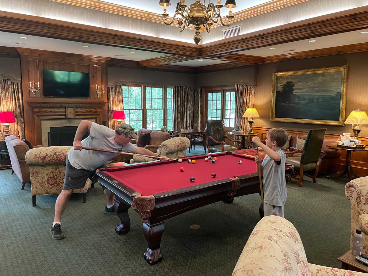 A dad and his young son play pool in one of the rooms, while on a family getaway to Blackberry Farm in Tennessee.