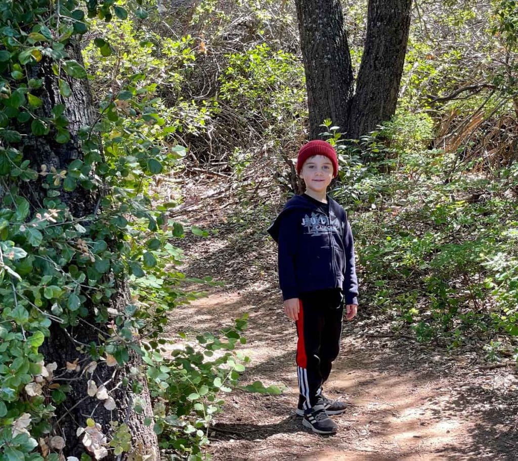 A young boy wearing a red cap hikes along a trail near Julia, CA.