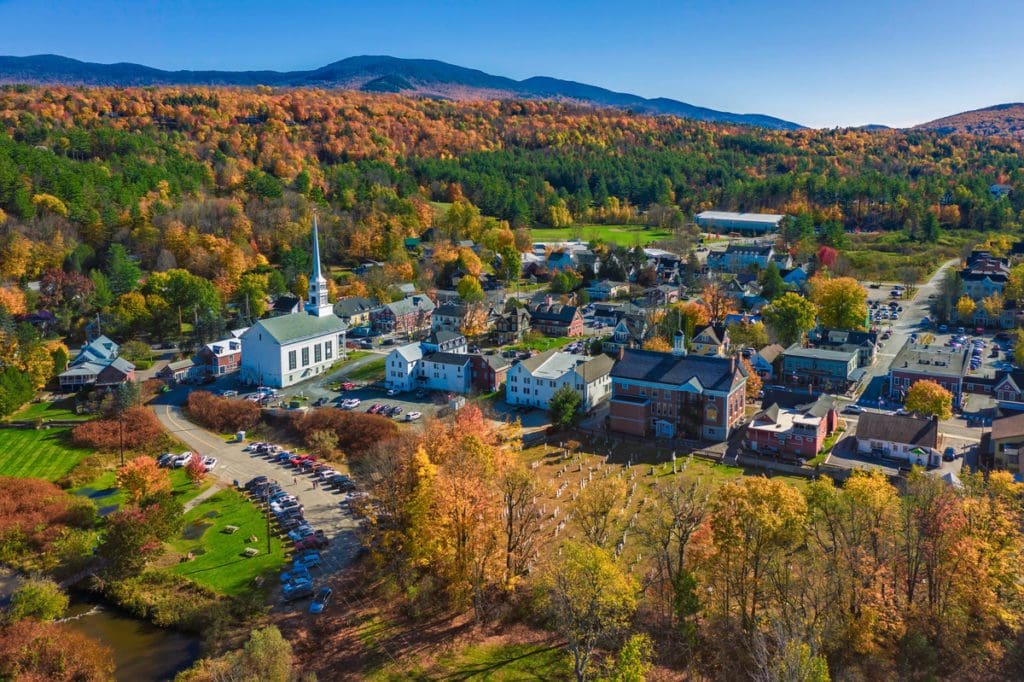 Aerial view of charming small town Stowe in Vermont, mountains with fall multicolor trees in the distance.